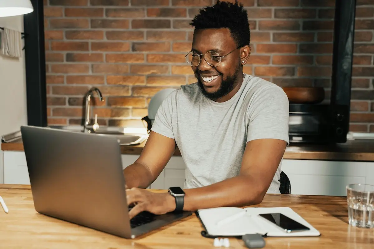 A smiling person typing on his laptop